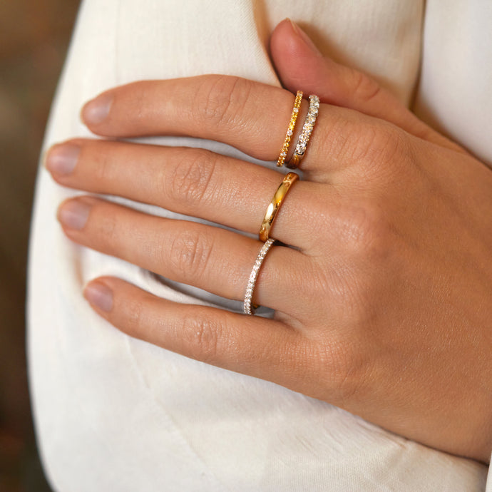Woman wearing multiple 18kt recycled gold and Platinum gemstone and diamond wedding rings on hand